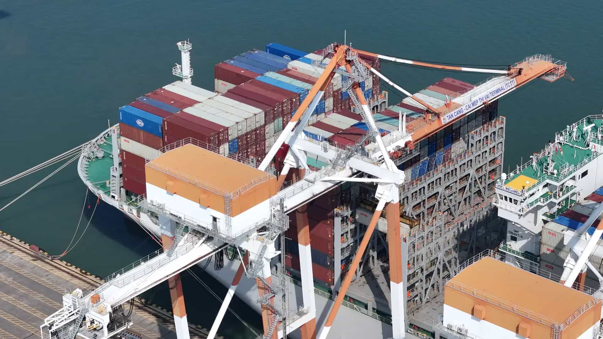 Vista aérea de um terminal de contêineres com pórticos operando ao lado de um navio